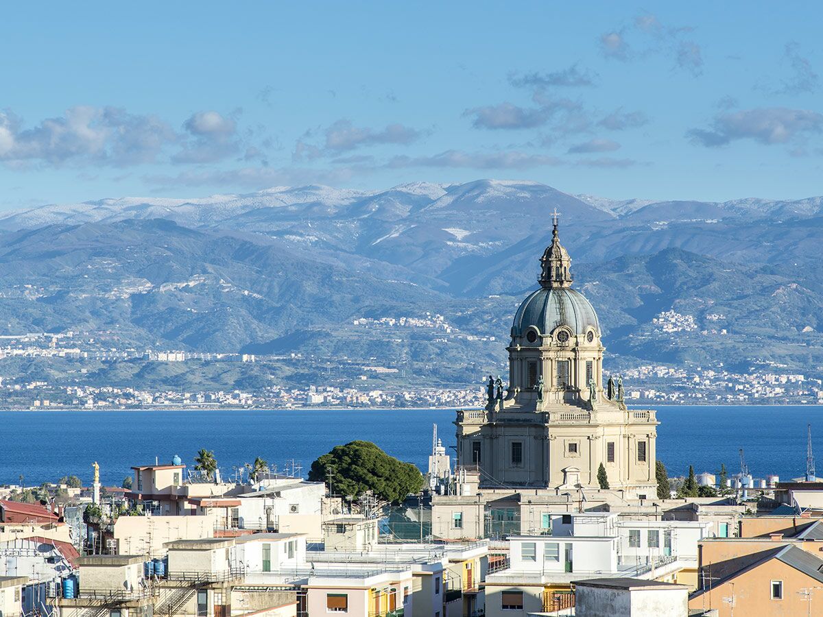 Panoramablick auf den Tempio Votivo di Cristo Re in Messina, Sizilien, mit verschneiten Bergen und Meer.