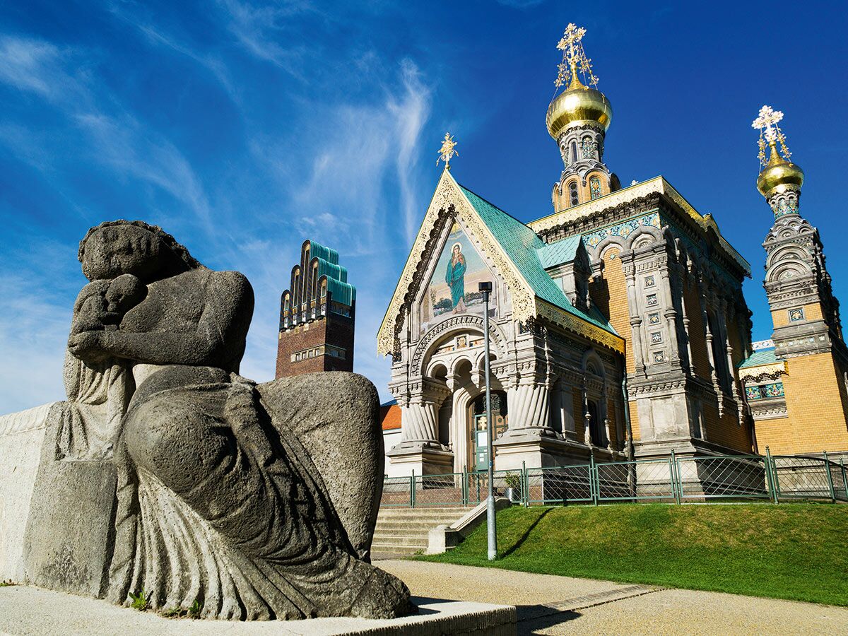 Russische Kapelle und Frauenstatue mit Kind auf der Mathildenhöhe in Darmstadt an einem sonnigen Tag.