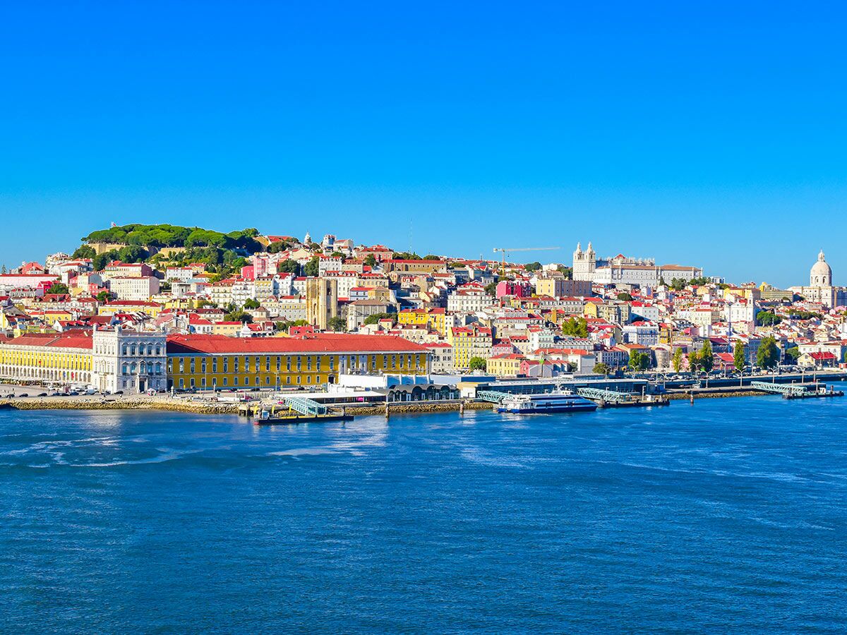 Panoramablick auf Lissabon, Portugal, mit bunten historischen Gebäuden, dem Tejo-Fluss und klarem blauem Himmel.