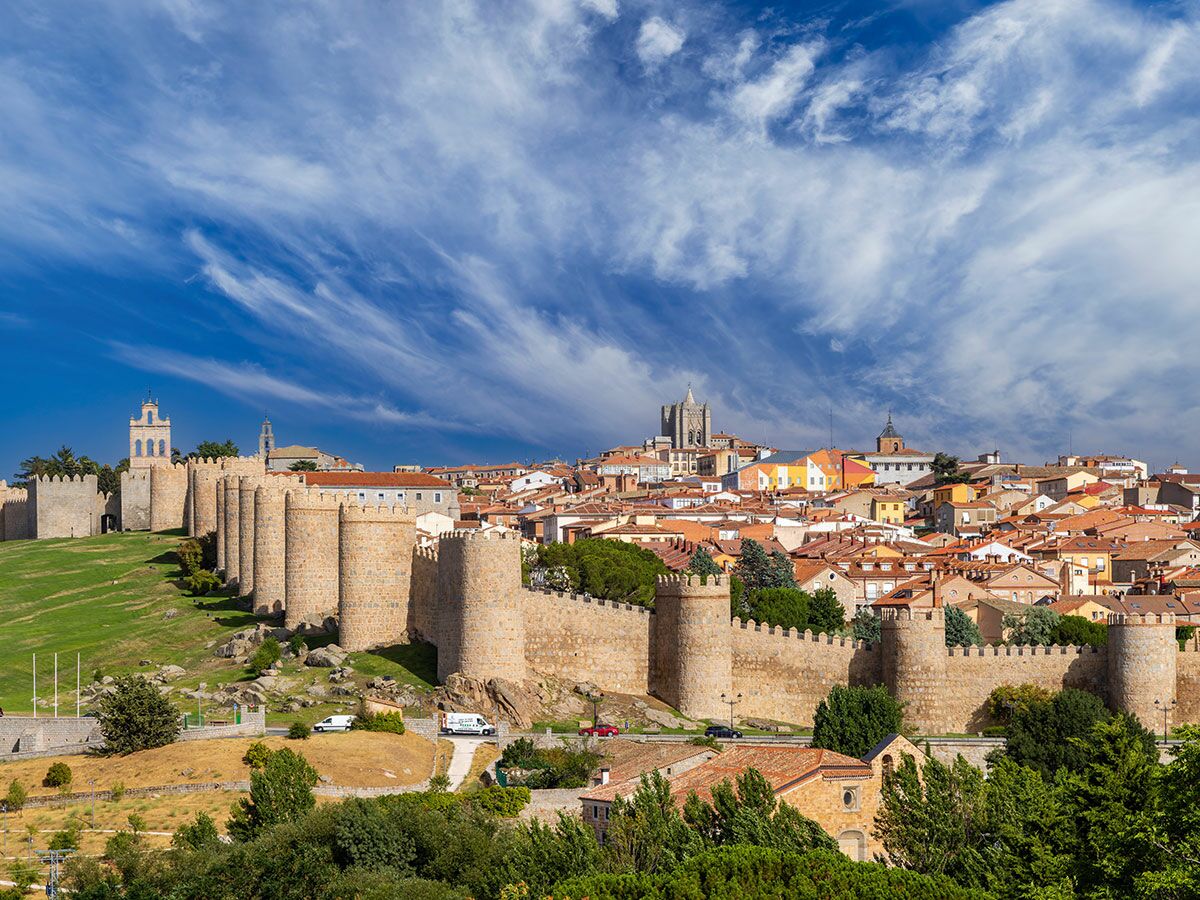 Panoramablick auf die mittelalterlichen Stadtmauern von Ávila, Spanien, mit Kathedrale und Altstadt unter blauem Himmel.