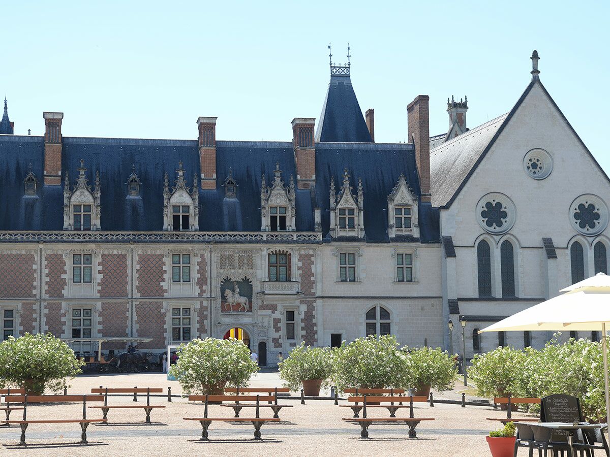 Historisches französisches Schloss mit Schieferdach, verzierten Gauben und Kaminen. Hof mit Bänken und Reiterstatue über dem Eingang.