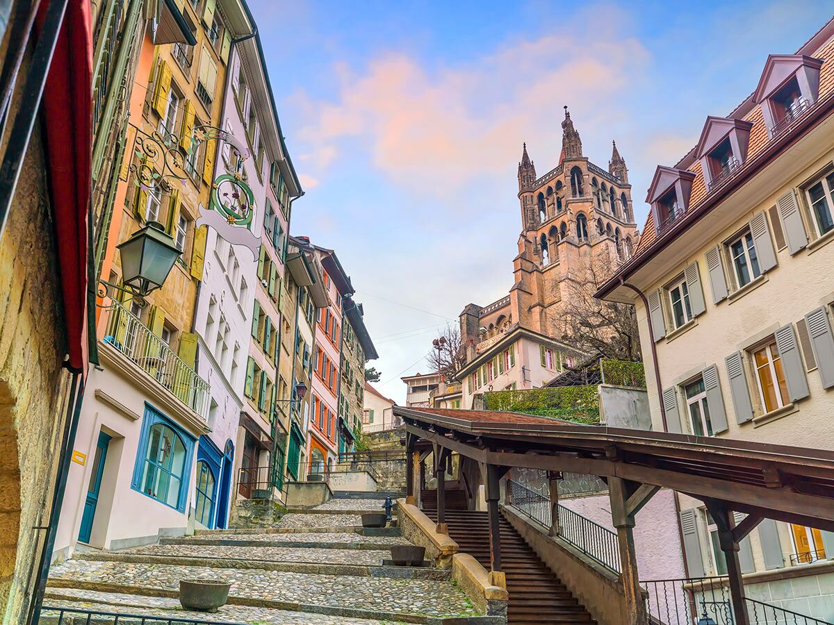 Blick auf die historischen Escaliers du Marché in Lausanne mit bunten Häusern und der Kathedrale im Hintergrund.