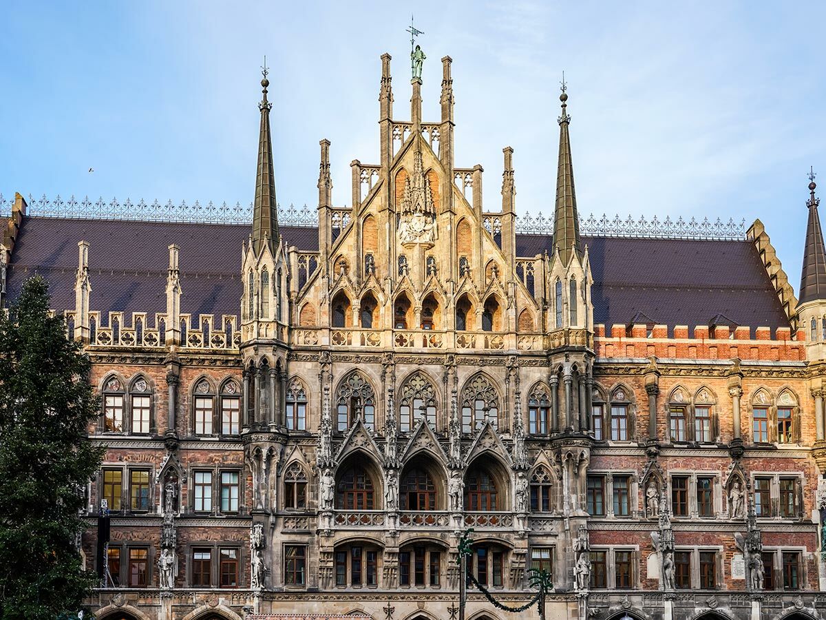 Ornate Neugotische Fassade des Neuen Rathauses in München mit zahlreichen Fenstern, Türmchen und Statuen unter blauem Himmel.