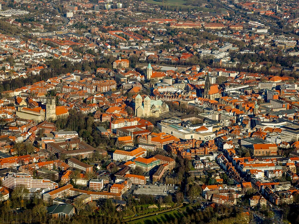 Luftbild der historischen Altstadt von Münster mit dem St. Paulus Dom und St. Lamberti Kirche unter blauem Himmel.