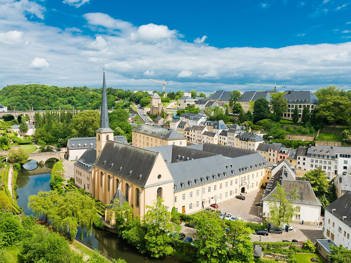 Panoramablick auf das historische Grund-Viertel in Luxemburg-Stadt mit der Abtei Neumünster, der Alzette und Brücken bei Sonnenschein.