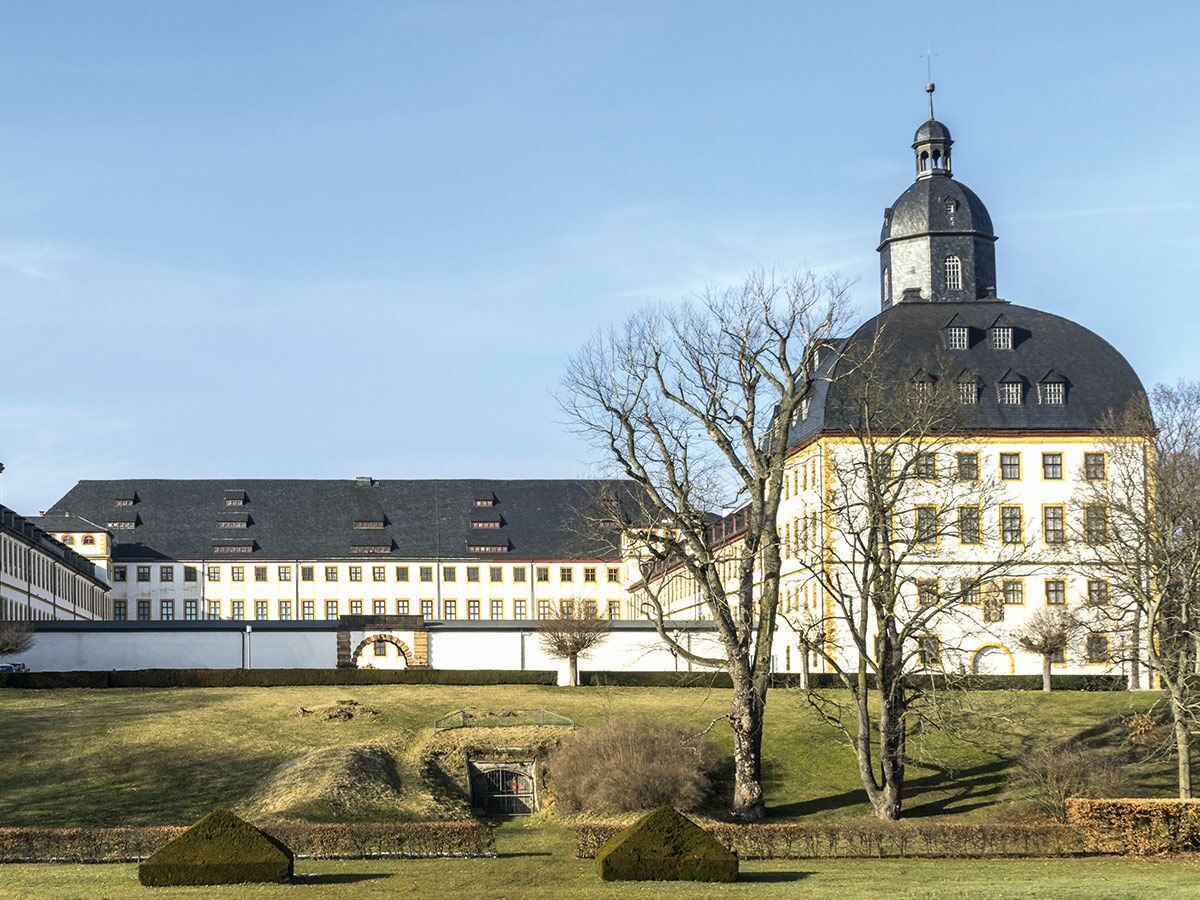 Historisches Schloss Friedenstein in Gotha, Deutschland, mit Kuppelturm und weißer Fassade, umgeben von Gärten.
