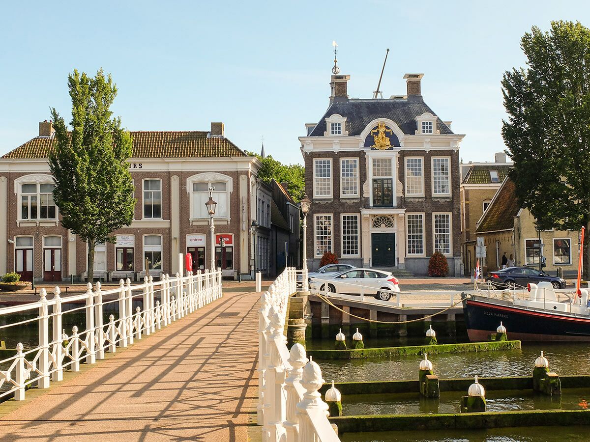 Malerische Ansicht einer historischen holländischen Grachtenstadt mit verzierter Brücke, prächtigen Gebäuden und Booten.