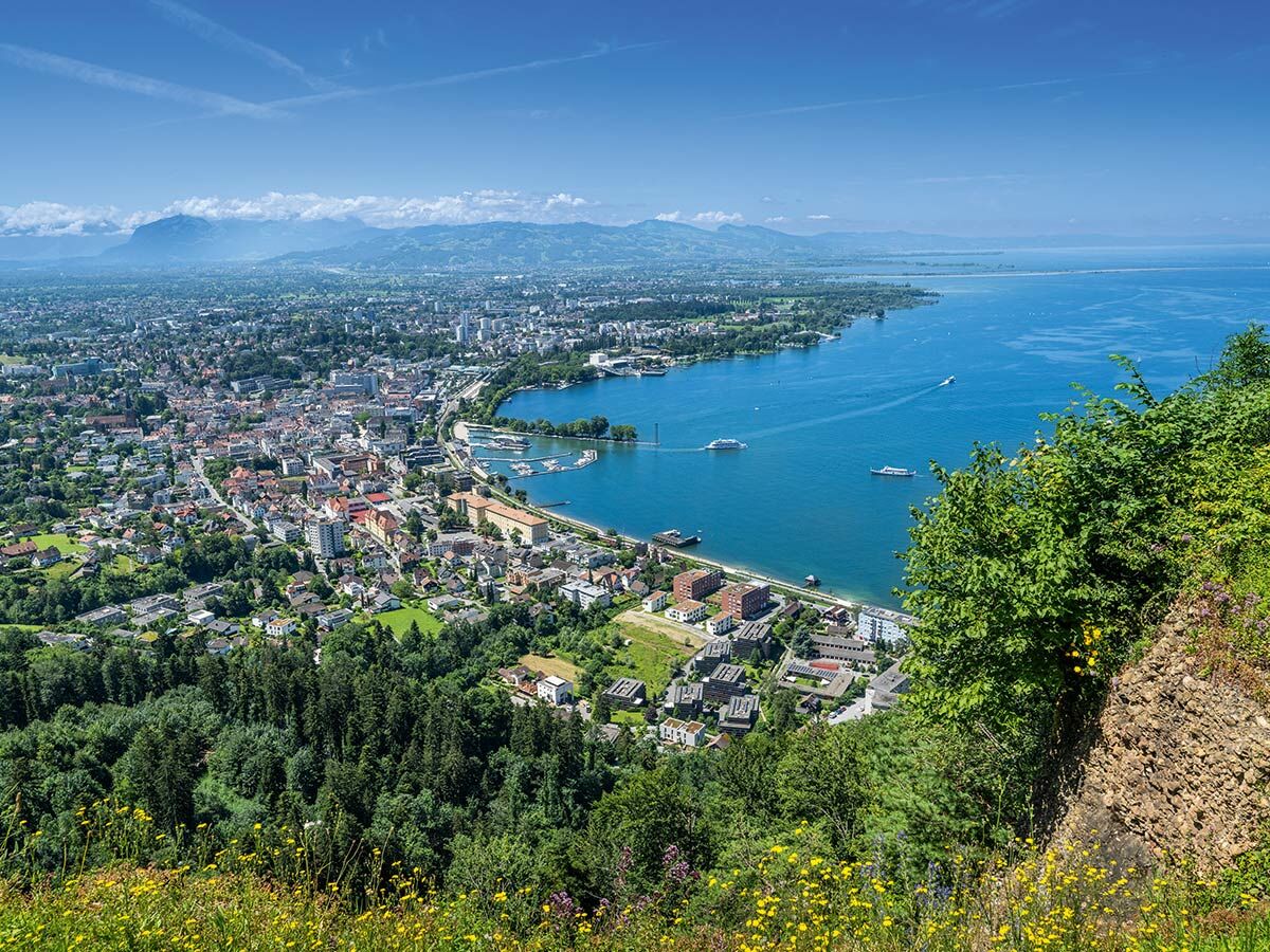 Luftaufnahme der malerischen Inselstadt Lindau am Bodensee mit Hafen, Altstadt und Bergen im Hintergrund.