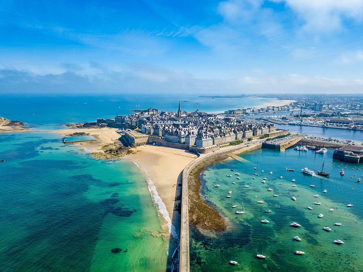 Luftaufnahme der historischen Küstenstadt Saint-Malo in der Bretagne, Frankreich, mit Stadtmauern, Stränden und einem Hafen voller Boote.