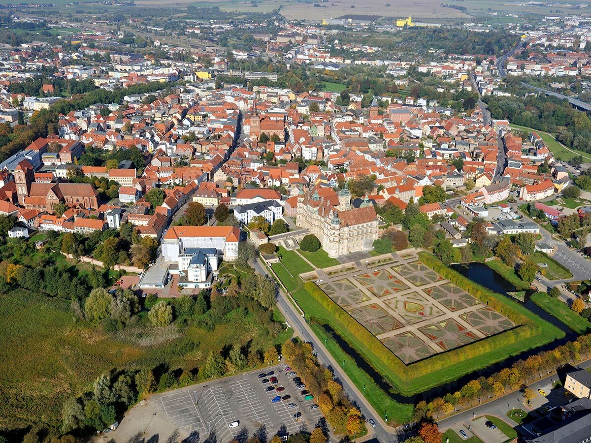 Luftaufnahme von Schloss Hartenfels und der historischen Altstadt Torgau mit barockem Garten, Elbe und roten Dächern in Deutschland.