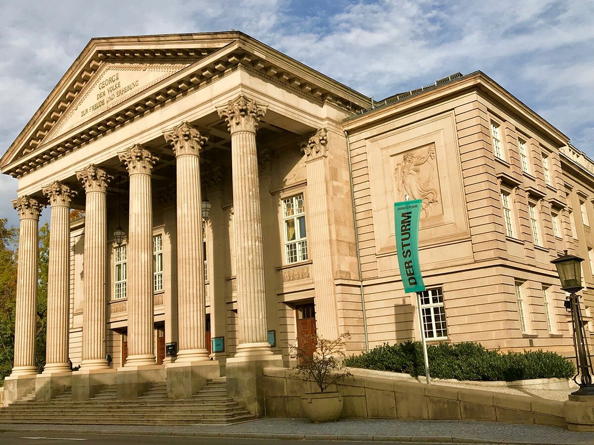 Historisches Meininger Staatstheater mit klassizistischer Fassade, großen Säulen und einem Banner für "Shakespeare: Der Sturm".