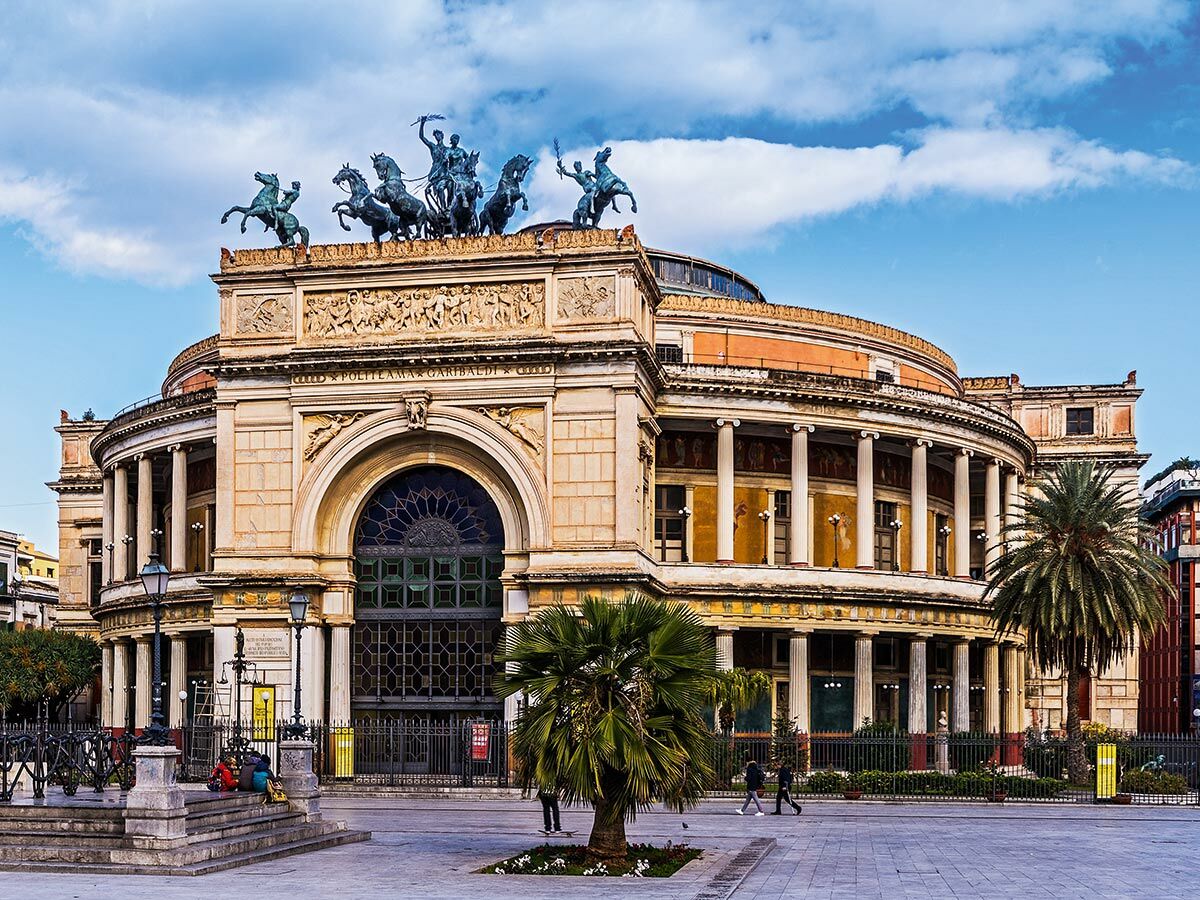 Neoklassizistisches Theater Politeama Garibaldi in Palermo, Sizilien, mit Reiterstatuen auf dem Dach und Palmen.