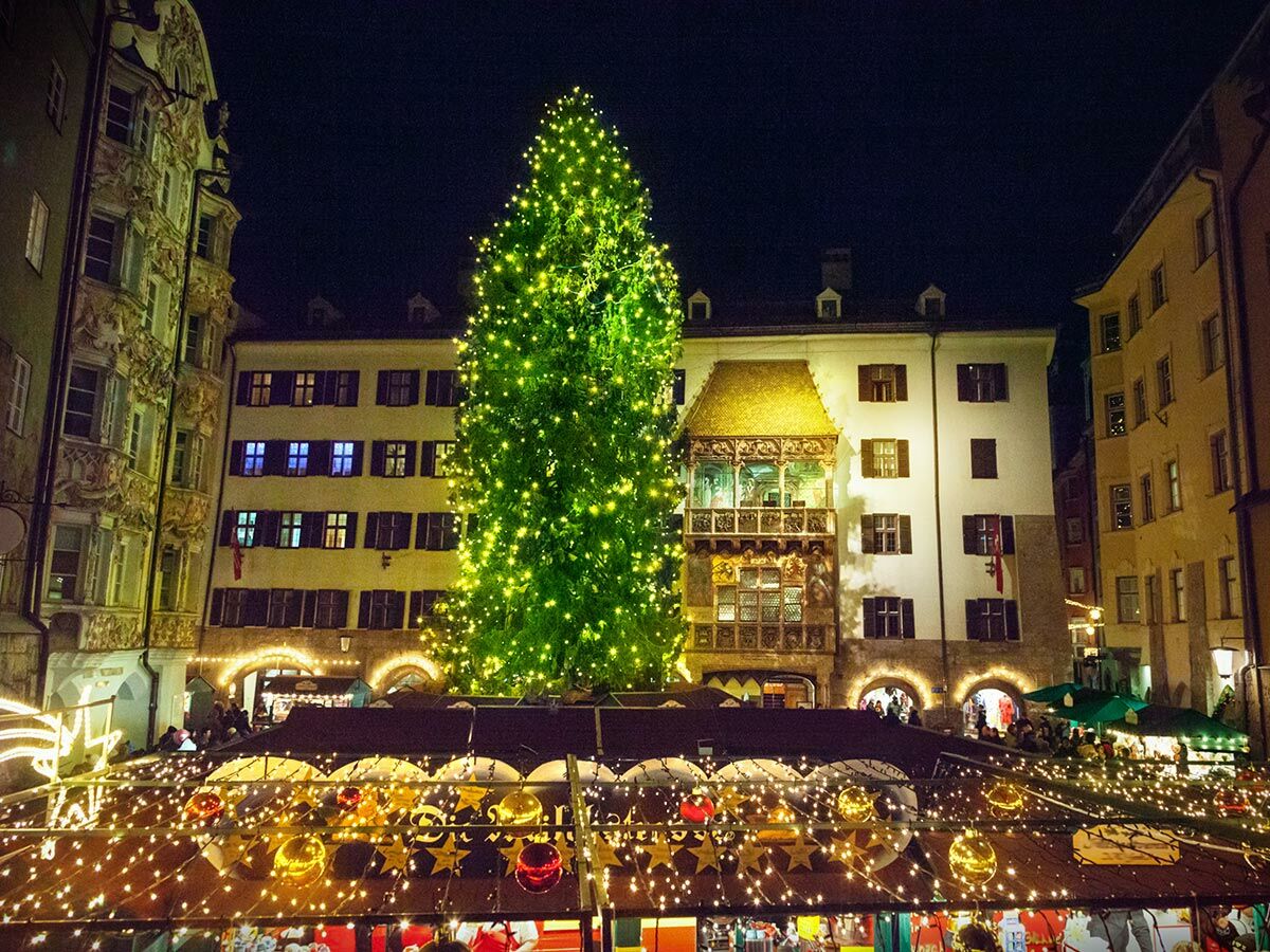 Festlicher Weihnachtsmarkt in Innsbruck bei Nacht mit beleuchtetem Christbaum und dem historischen Goldenen Dachl.