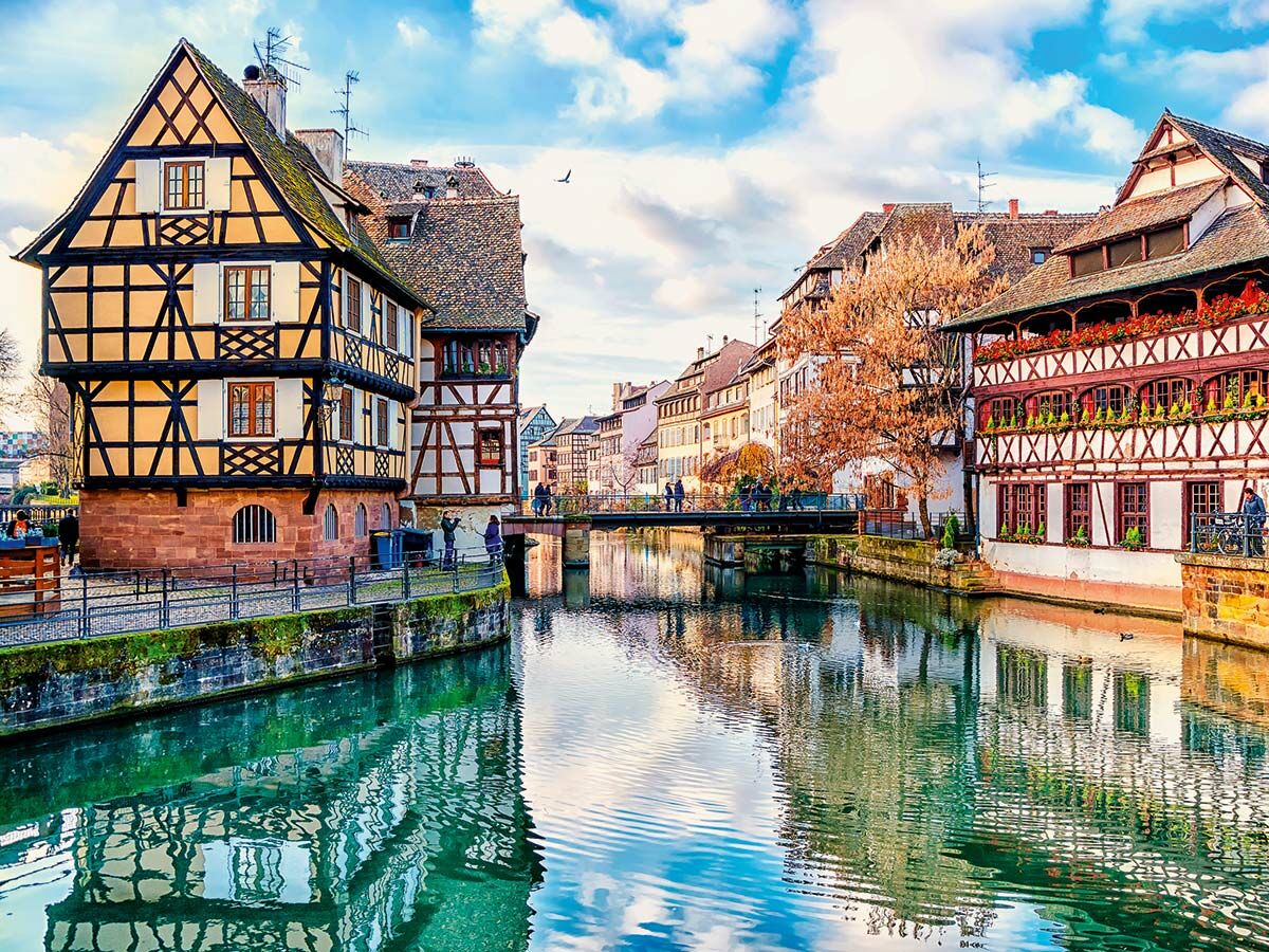 Malerische Fachwerkhäuser in Straßburgs Petite France Viertel am Kanal mit Brücke, Menschen und Reflexionen.