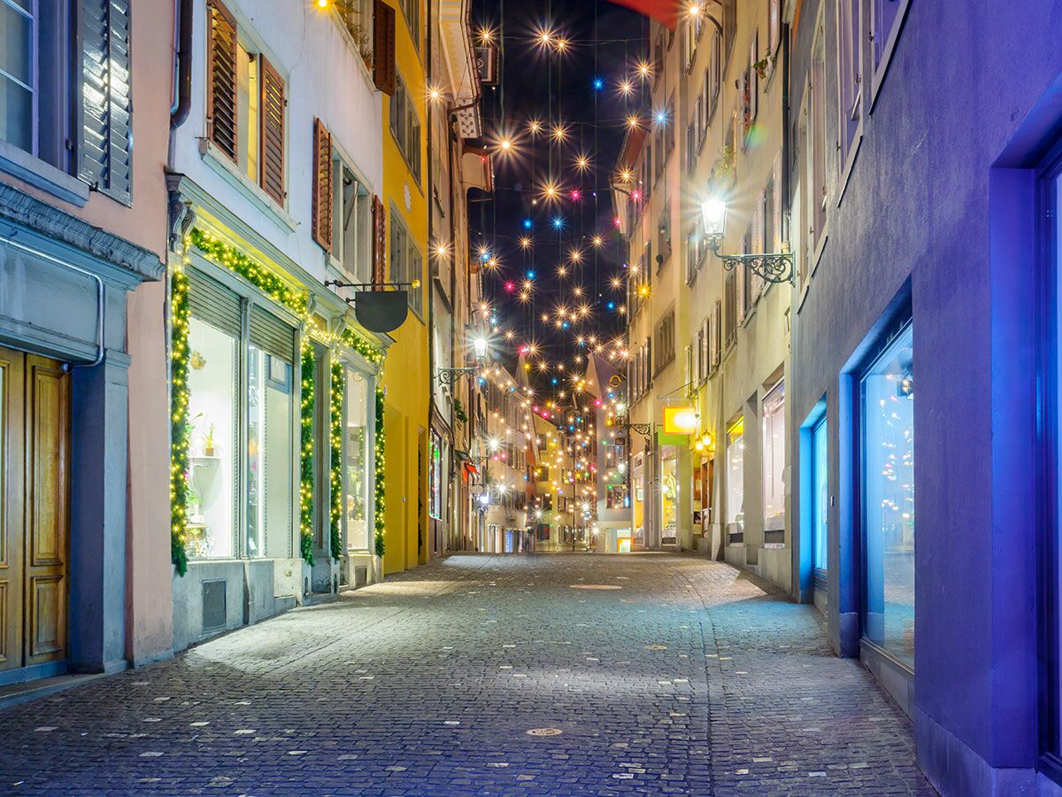 Festlich beleuchtete Gasse bei Nacht mit hängenden Sternenlichtern und dekorierten Schaufenstern in einer europäischen Altstadt.
