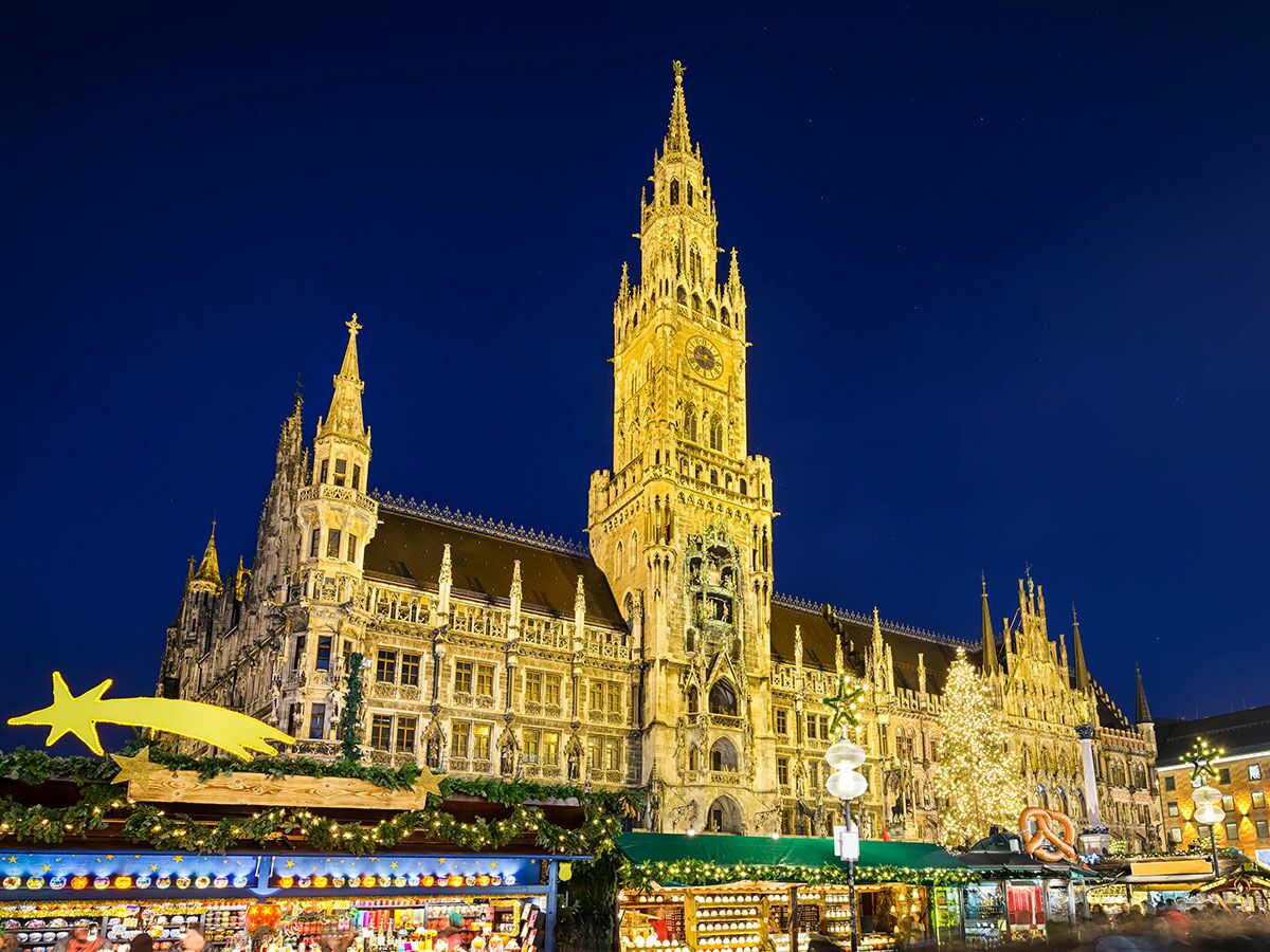 Festlich beleuchtetes Neues Rathaus München und Christkindlmarkt auf dem Marienplatz bei Nacht mit Marktständen und Weihnachtsbaum.