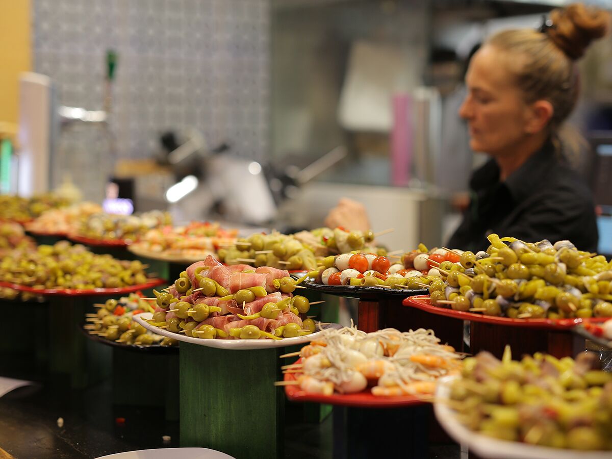 Bunte Auswahl spanischer Tapas und Pinchos mit Oliven, Schinken, Tomaten am Buffet einer Bar.