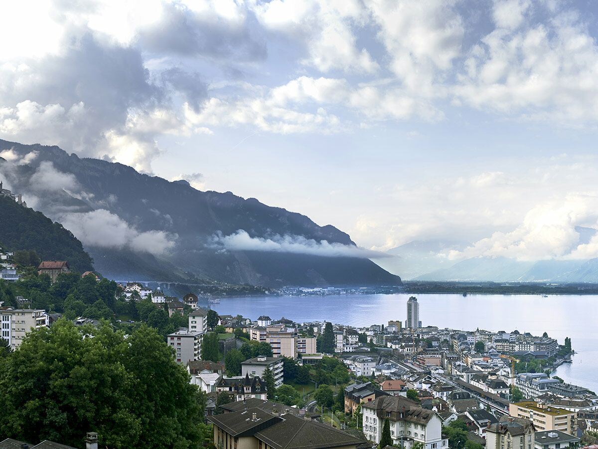 Panoramablick auf die Stadt Montreux am Genfersee mit bewölkten Bergen und den Alpen im Hintergrund.