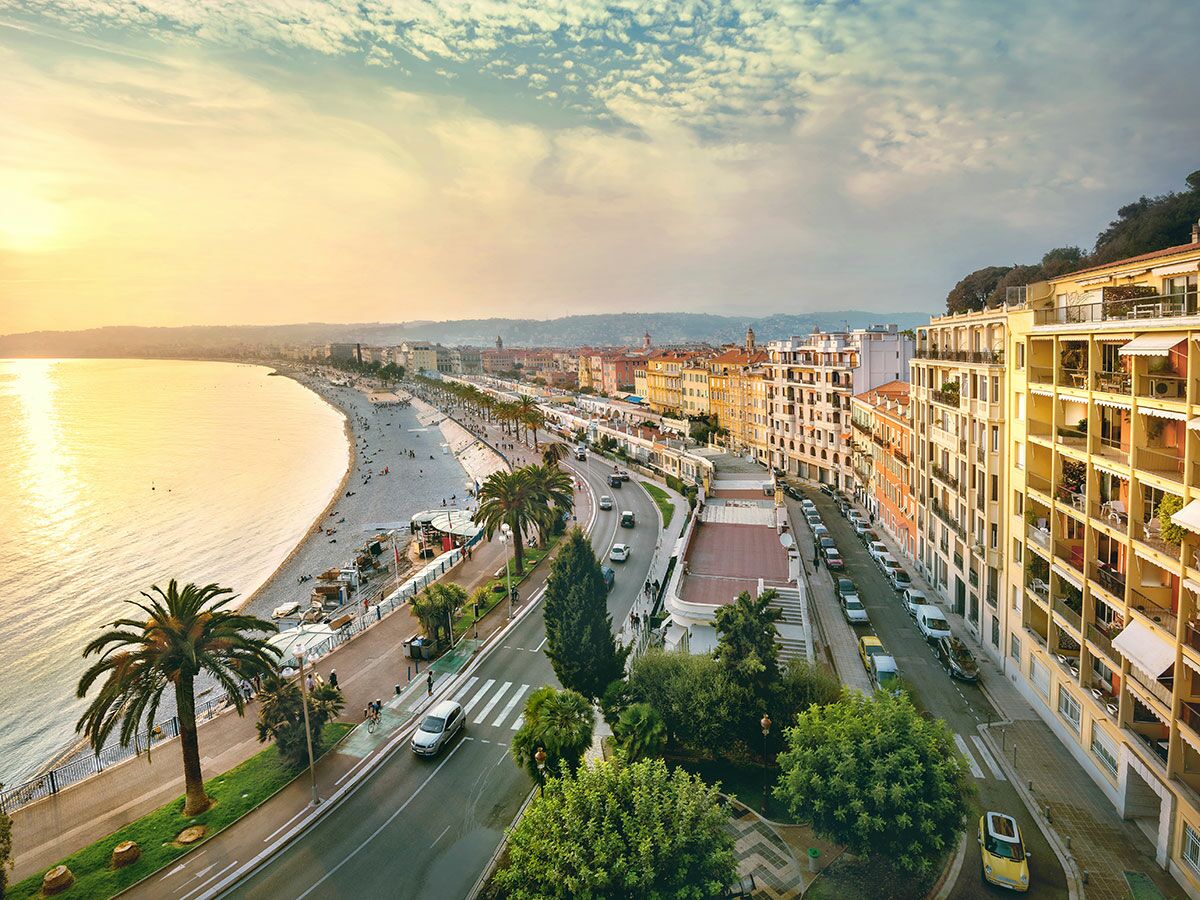 Panoramablick auf Nizza, Frankreich, bei Sonnenuntergang mit Promenade des Anglais, Strand, Meer und Stadtgebäuden.