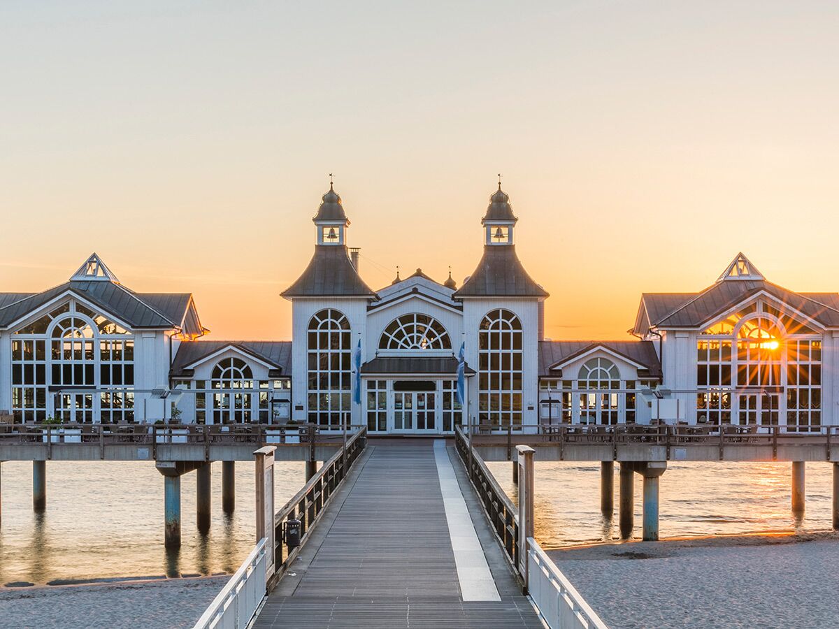 Die historische Seebrücke Sellin auf Rügen bei Sonnenuntergang, mit ihren weißen Jugendstil-Gebäuden, Türmen und einem langen Pier.