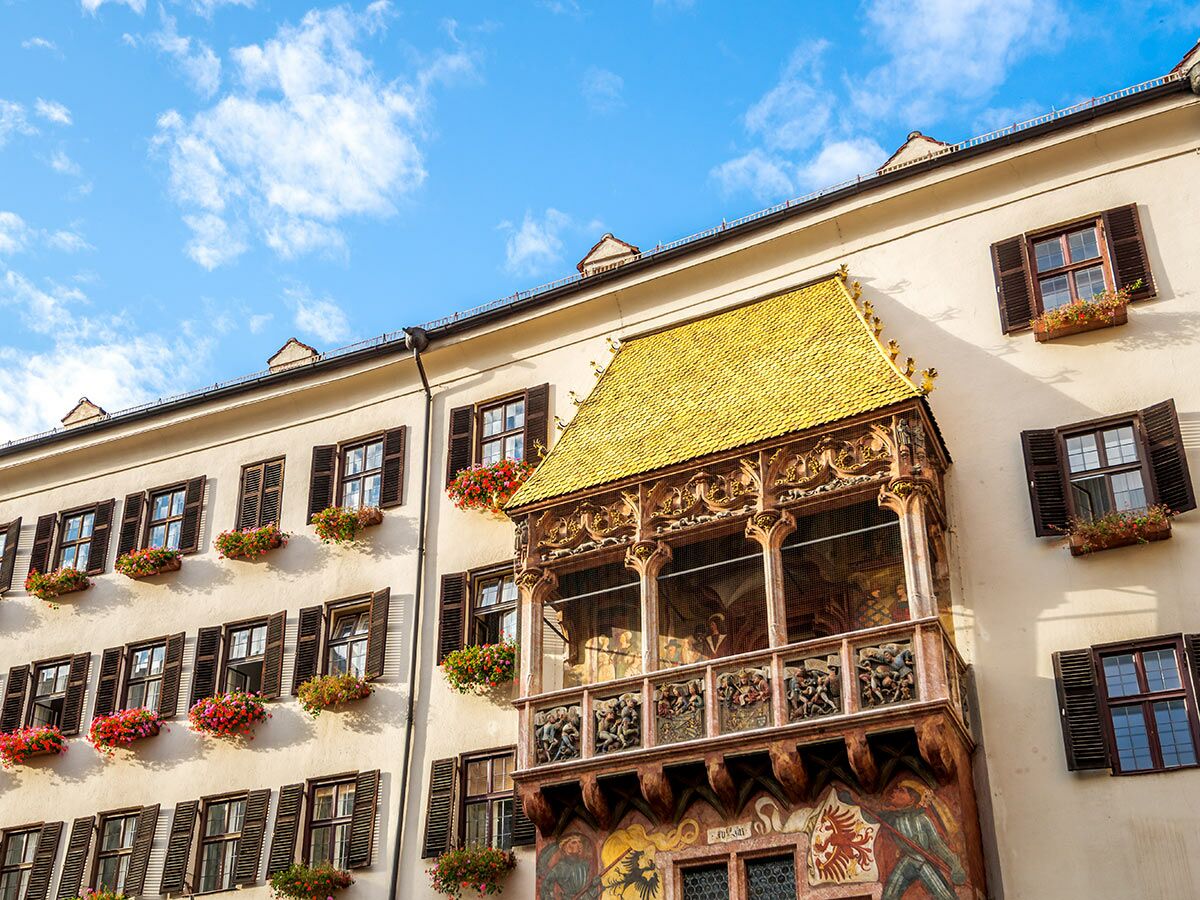 Historisches Goldenes Dachl in Innsbruck, Österreich, mit goldener Überdachung, geschnitztem Balkon und bunten Blumenkästen.