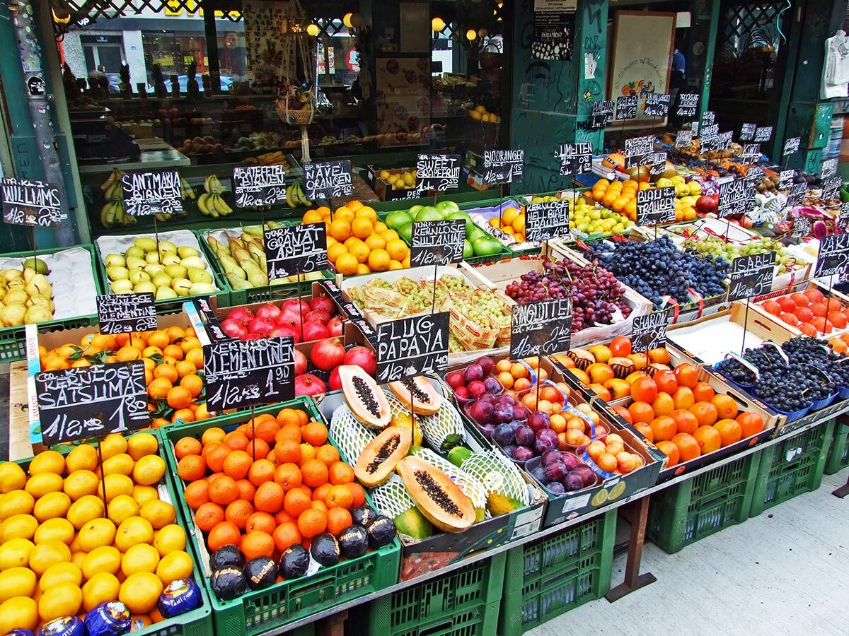 Lebhafter, bunter Obststand auf einem Straßenmarkt mit einer großen Auswahl an frischen Früchten wie Orangen, Äpfeln, Trauben und Papayas.