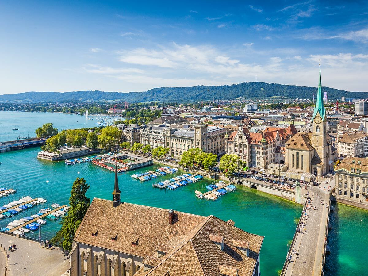 Panorama von Zürich mit Fraumünsterkirche, Limmatfluss, Zürichsee und vielen Booten unter blauem Himmel.