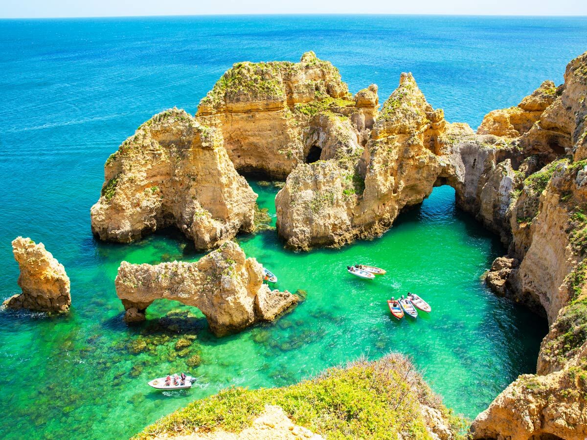 Spektakuläre Felsformationen und Meereshöhlen an der Algarveküste Portugals mit türkisfarbenem Wasser und Booten.