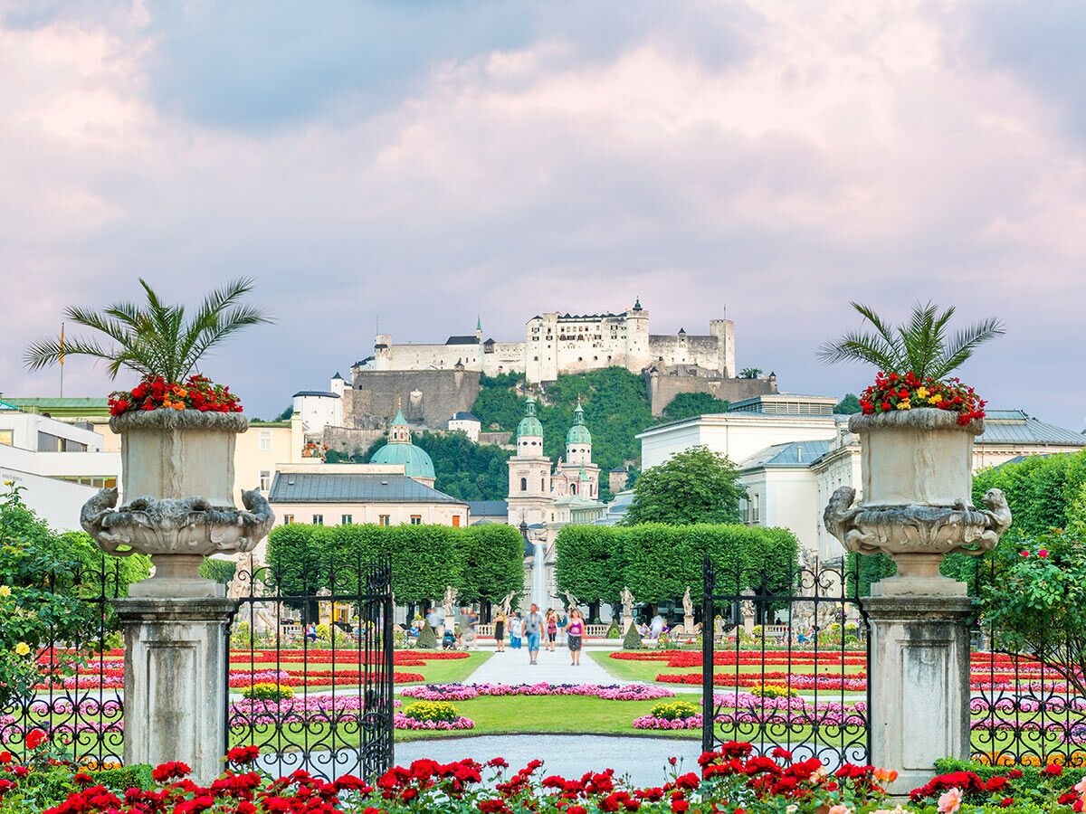 Blick durch den Mirabellgarten Salzburg mit farbenfrohen Blumenbeeten und Ziergefäßen auf die Festung Hohensalzburg.