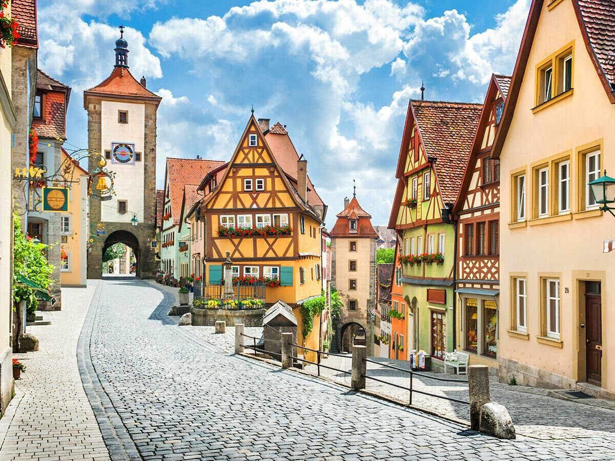 Malerische Gasse Plönlein in Rothenburg ob der Tauber mit Fachwerkhäusern, Kopfsteinpflaster und historischem Turm unter blauem Himmel.