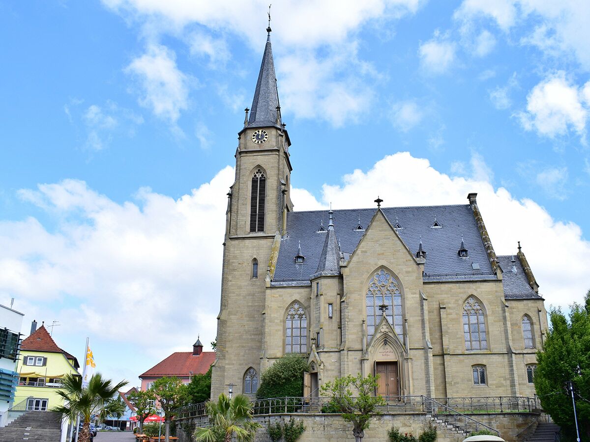 Historische Evangelische Stadtkirche in Weil der Stadt mit Glockenturm, steinernem Bau und blauem Himmel.
