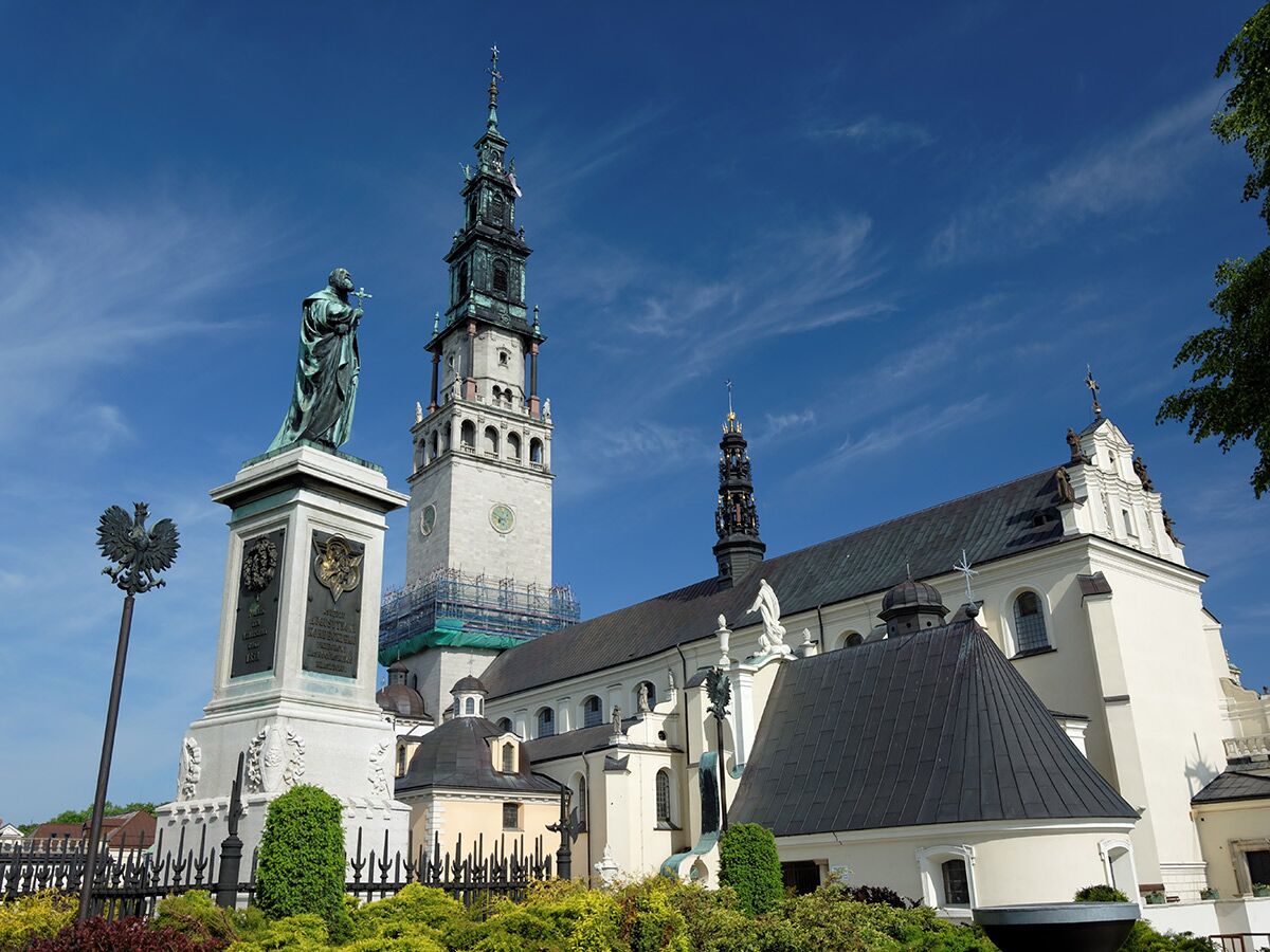 Das berühmte Jasna Góra Kloster in Częstochowa, Polen, mit hohem Glockenturm, Statue und polnischem Adler vor blauem Himmel.