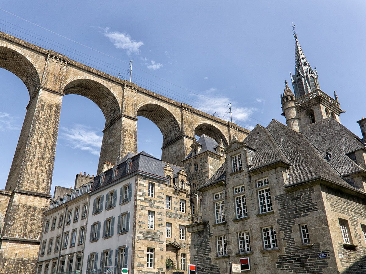 Blick auf das imposante Morlaix Viadukt aus Stein, das über historische Häuser und die Kirche Saint-Mélaine in Morlaix, Bretagne, Frankreich, ragt.