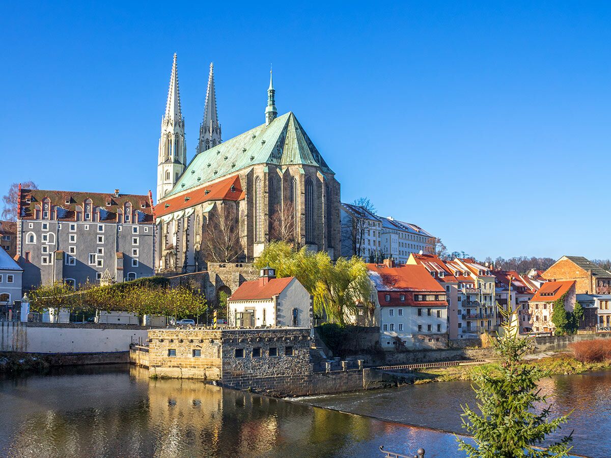 Panoramablick auf die historische Görlitzer Altstadt mit der Peterskirche, roten Dächern am Neiße-Fluss unter blauem Himmel.