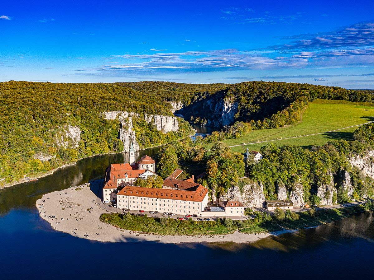 Luftaufnahme von Kloster Weltenburg, einer Benediktinerabtei am Ufer der Donau, umgeben von steilen Felsen und Wäldern in Bayern.
