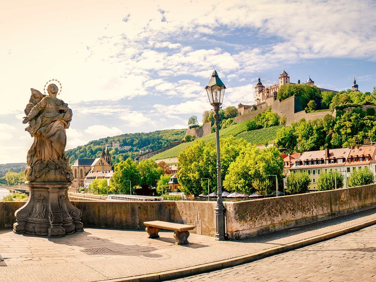 Historische Alte Mainbrücke Würzburg mit Heiligenstatue, Blick zur Festung Marienberg, Weinbergen und Main.