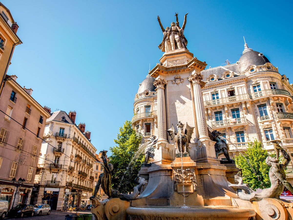 Historischer Brunnen Place de la Victoire Clermont-Ferrand, mit Skulpturen von Vercingetorix, Sieg, Drachen und Meerjungfrauen vor Altbau.