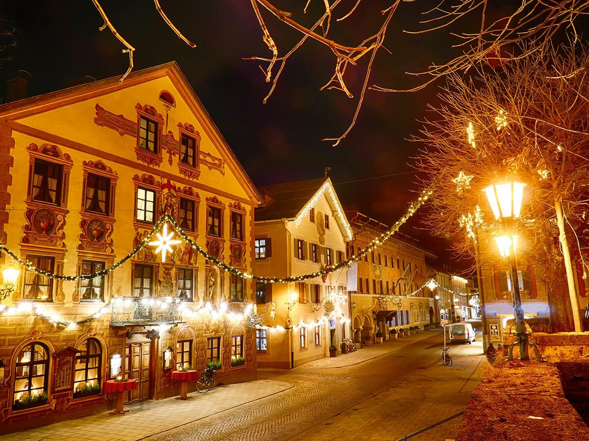 Festlich beleuchtete Altstadtstraße bei Nacht zur Weihnachtszeit. Historische Gebäude, Lichterketten, Sterne und Laternen.