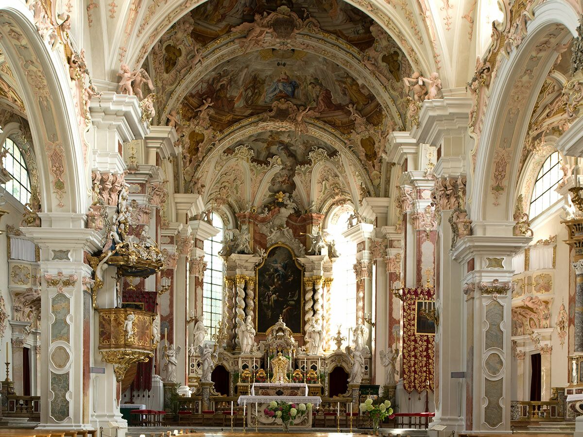 Prunkvolle Innenansicht einer barocken oder Rokoko-Kirche mit Hochaltar, Kanzel, Fresken und Stuckarbeiten.