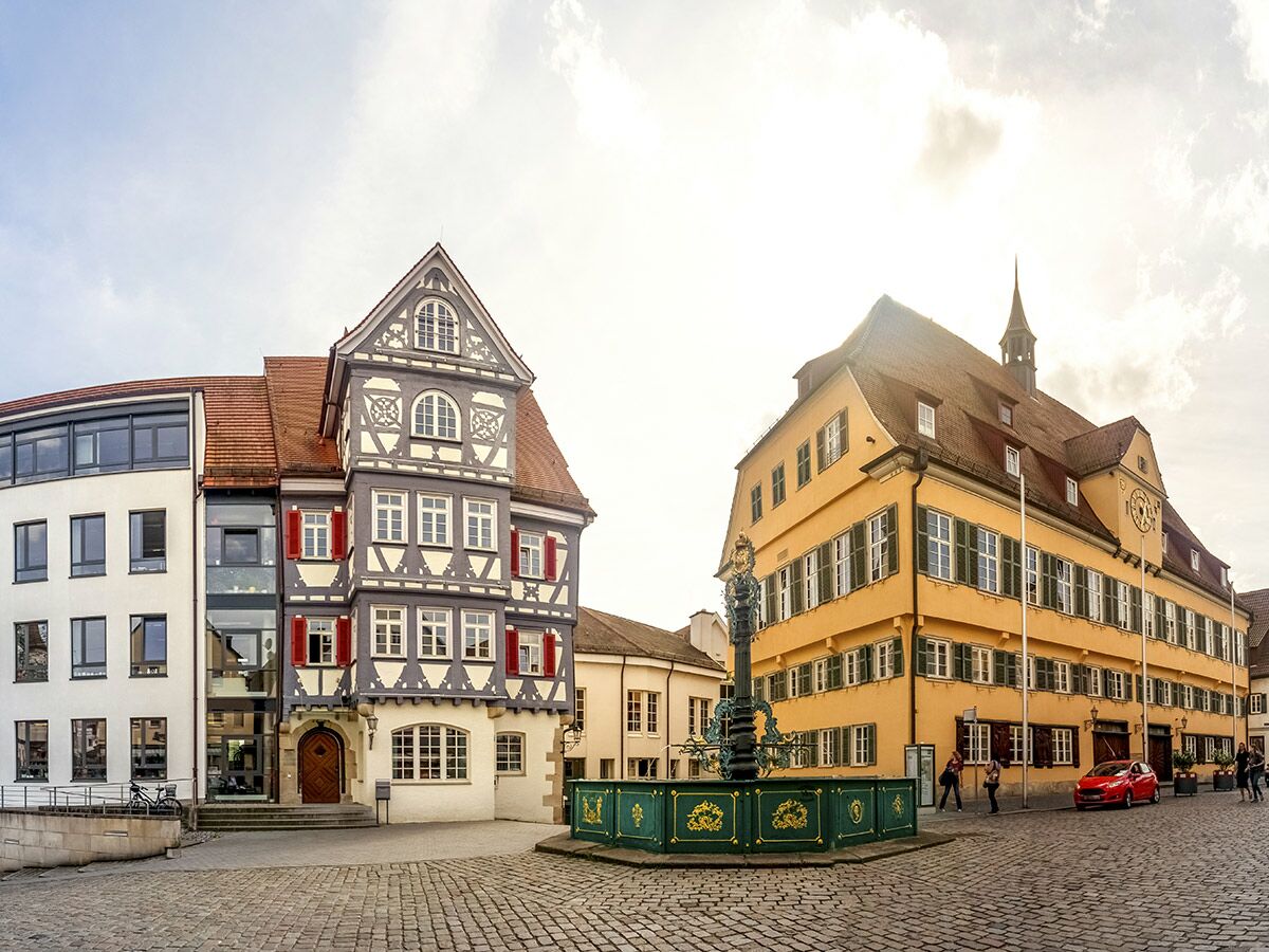 Historischer Marktplatz in einer deutschen Altstadt mit Fachwerkhaus, Rathaus, Brunnen und Kopfsteinpflaster bei Sonnenschein.