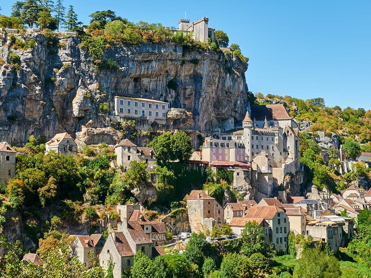 Blick auf die historische Felsenstadt Rocamadour in Südfrankreich mit ihren Häusern am steilen Felsen und dem Schloss oben.