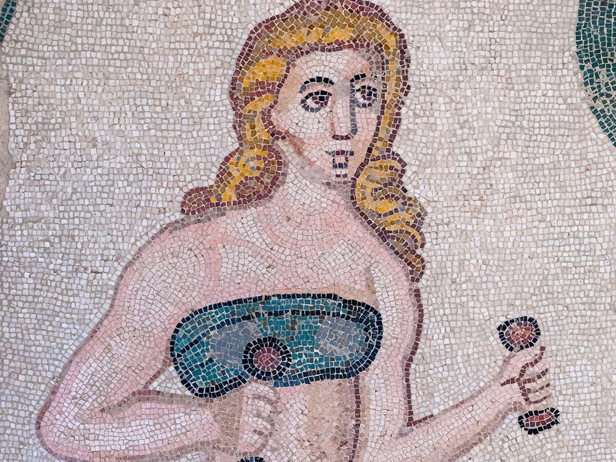 Römisches Mosaik einer Athletin mit blonden Zöpfen und blauem Bustier, die eine Hantel hält, aus Villa Romana del Casale.