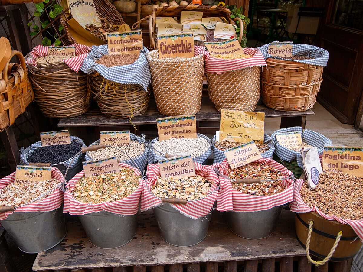 Verschiedene italienische Hülsenfrüchte, Bohnen und Suppenmischungen in Körben und Eimern auf einem Bauernmarkt.