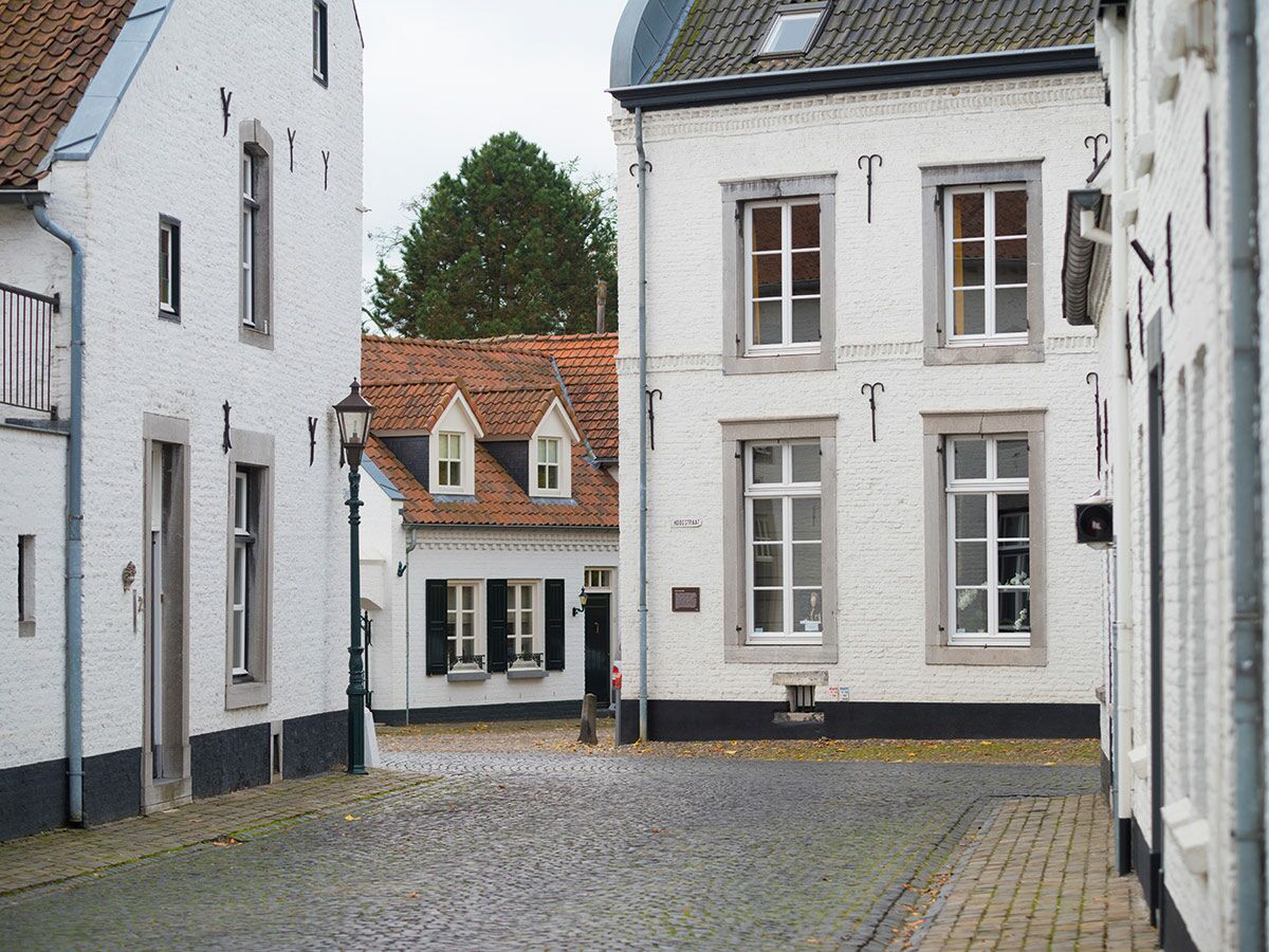 Malerische Gasse mit traditionellen weißen Backsteinhäusern, roten Ziegeldächern und Kopfsteinpflaster in einer Stadt.