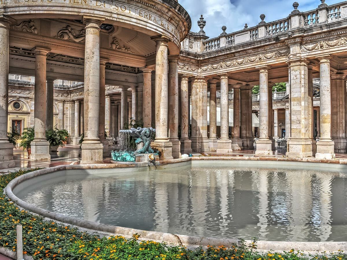 Historische Thermenanlage Montecatini Terme, Italien, mit Säulen, Meerjungfrauenbrunnen und spiegelndem Wasserbecken.