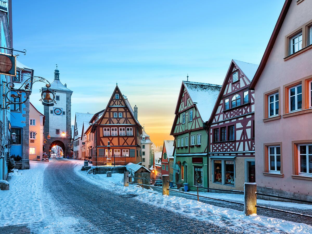 Winterlicher Abend in Rothenburg ob der Tauber mit schneebedeckter Altstadt, Fachwerkhäusern und historischem Turm.