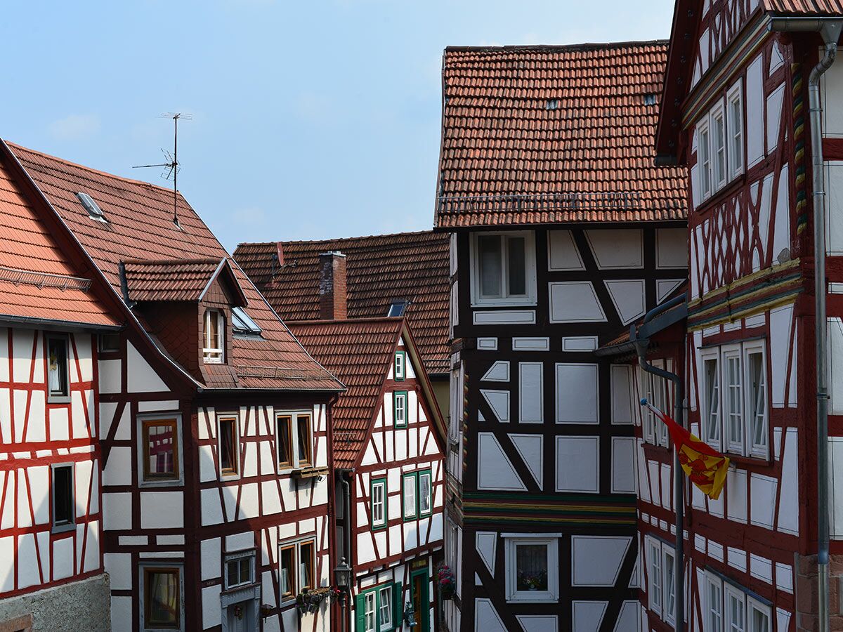 Ansicht mehrerer traditioneller Fachwerkhäuser mit roten Ziegeldächern und weißen Fassaden in einer deutschen Altstadt.