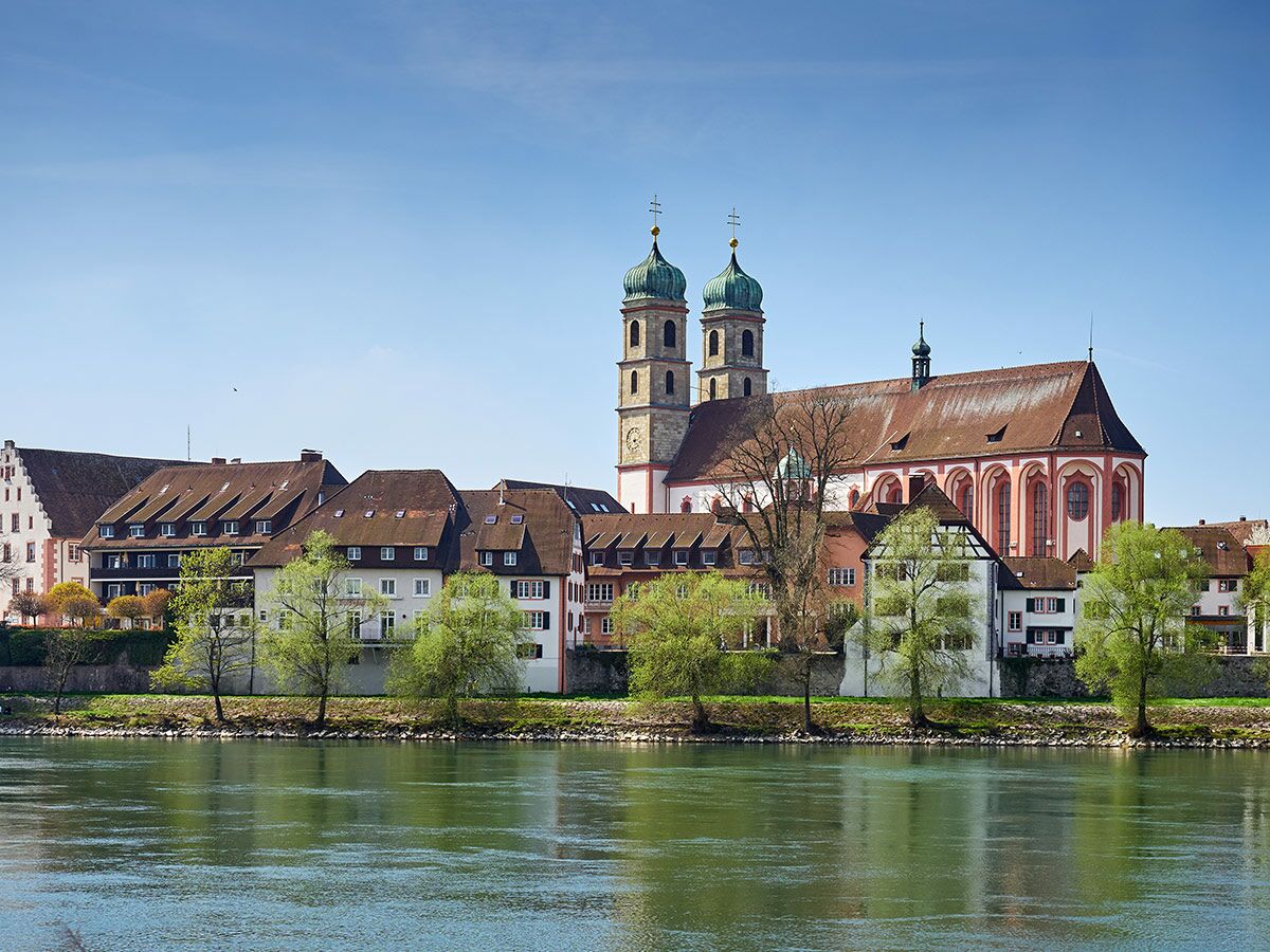Historisches Bad Säckingen mit Kirche St. Peter und Paul, grünen Türmen, Altstadt am Rhein unter blauem Himmel.