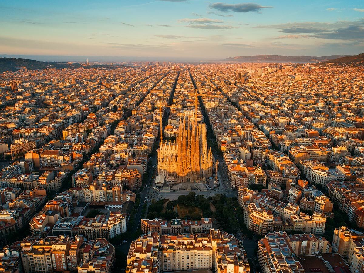 Luftaufnahme der Sagrada Familia und Barcelonas Eixample-Viertel bei goldenem Licht des Sonnenuntergangs oder Sonnenaufgangs.