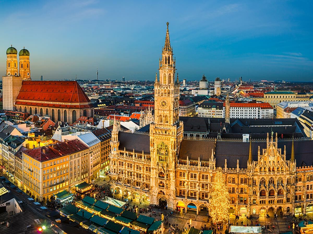 Panoramablick auf den Marienplatz in München bei Dämmerung mit Neuem Rathaus, Frauenkirche und beleuchtetem Weihnachtsmarkt.